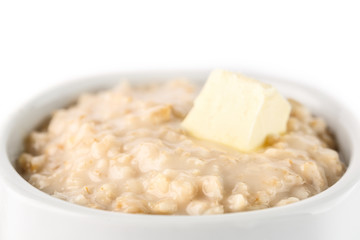 breakfast: oatmeal porridge with butter in white bowl on white background. Isolated