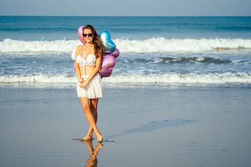 young and beautiful girl holding air helium balloons on the sea. holiday and vacation concept