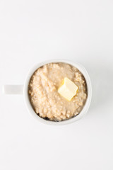breakfast: oatmeal porridge with butter in white bowl on white background. Top view. Isolated