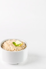 breakfast: oatmeal porridge with butter in white bowl on white background. Isolated
