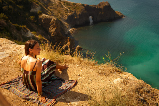 A beautiful young girl,in the background azure,clean sea,summer day.Crimea. Sevastopol.Grot of Diana. Place of power.Rocky shore of the ocean.Joy. Vacation.Recreation.Pleasure.Love.Freedom.Wildness. 