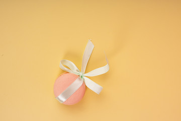 Pink pasta macaroons, tied with a gift ribbon with a bow, on a yellow background