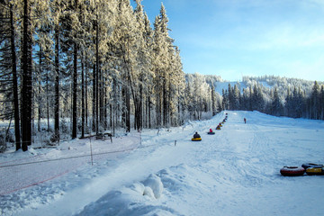 people on snow tubes down hill at winter day