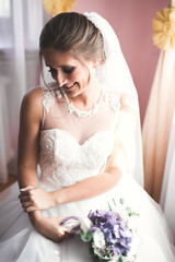 Naklejka premium Gorgeous bride in robe posing and preparing for the wedding ceremony face in a room