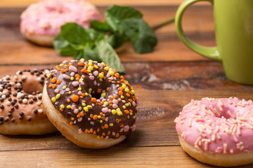 Coffee and donut. pink donut with a cup of tea on a dark wooden background. tasty breakfast.