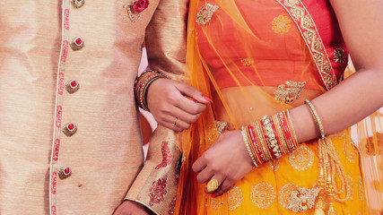 Indian bride and groom holding hands together during a wedding.