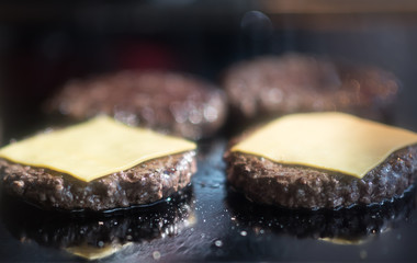 Hamburger cutlet frying on pan.Natural meet loaf pieces cooking in the kitchen.Burger sandwich meat being cooked with a lot of white smoke from a fat and oil. cheese on the cuttlets