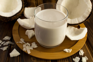 Coconut  milk in the glass on the round wooden cutting board