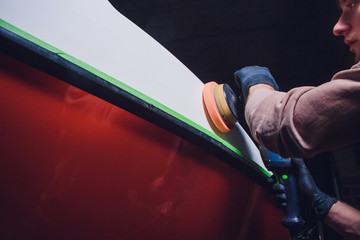 Yacht maintenance. Man polishing side boat polishing grinder machine in marina
