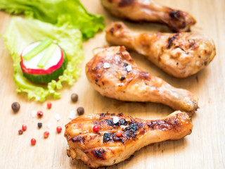 Grilled chicken drumsticks on a wooden Board with fresh vegetables Selective focus