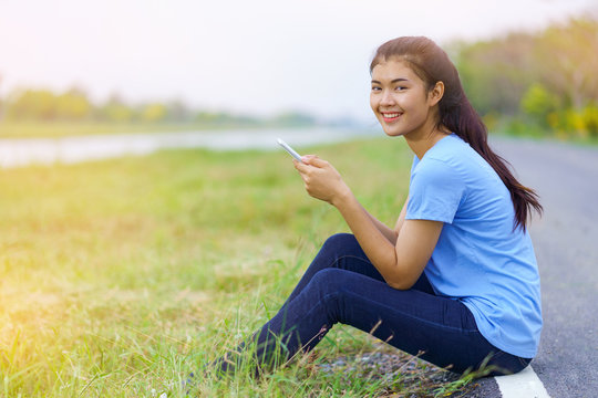 Portrait of beautiful girl in blue t-shirt and jeans smiling with phone on hands