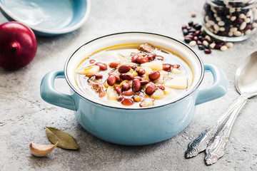 Vegan vegetable and bean soup in a pot on concrete background. Selective focus, space for text. 