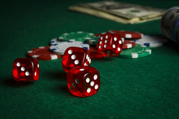 Dice on the poker table against the background of poker chips and dollars