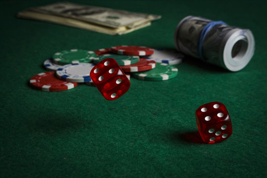 Dice on the poker table against the background of poker chips and dollars