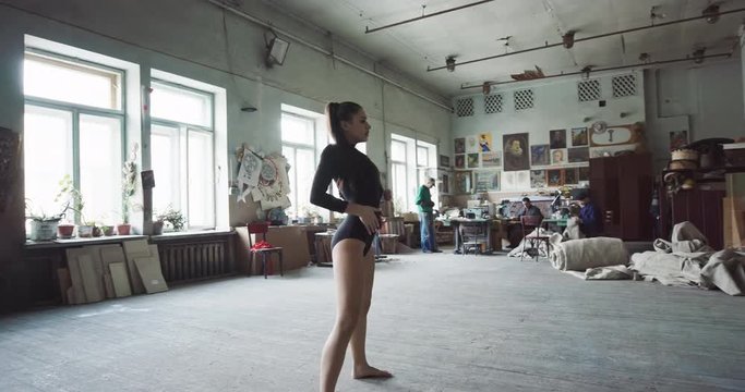 Pretty young girl dancing contemporary dance in the spacious big art studio. Woman trains the flexibility of her body
