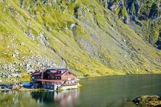 Daylight view to Balea Lake cottage with green mountains