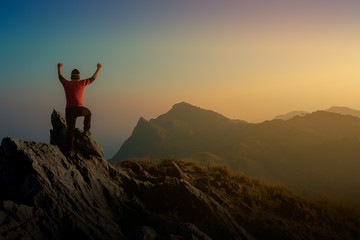 A man standing show hand on the top of the big mountain, a man success the bussiness