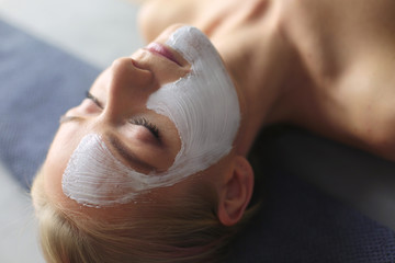 Naklejka premium Face mask.Beautiful young girl at spa ,cosmetician woman applying facial mask.
