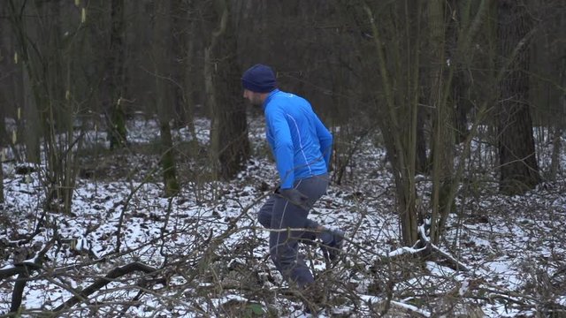 Young man jogging in winter forest, super slow motion
