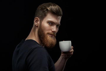 Young happy bearded man drinking morning fresh expresso coffee Caucasian handsome male business professional having coffee indoors close up studio portrait Side view portrait of stylish hairstyle man.