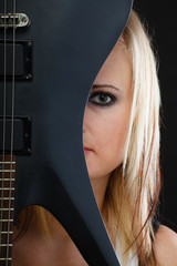 Blonde woman holding electric guitar, black background