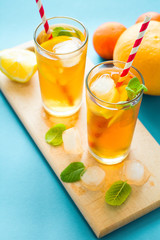Fototapeta premium Glasses of iced tea with lemon slices and mint on turquoise wooden background