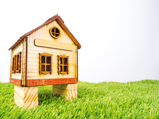 Model traditional wooden house on stilts. Wooden house toy on green grass. Isolated wooden toy house with pier angle view. Concept of the Earth Day. Copy space