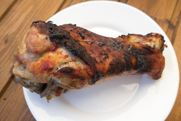Appetizing roast turkey shank on a plate close up