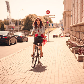 Woman with bike riding down the city street