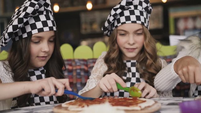 Cheerful girls in uniform cooking a pizza, on master class of chief in cafe