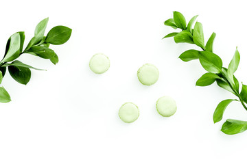 Summer background with green leaves and sweets macarons on white top view copy space