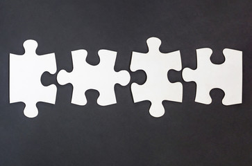 Four disconnected jigsaw puzzle pieces in row on black background
