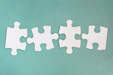 Four empty disconnect pieces of puzzle in row against background of green pastels