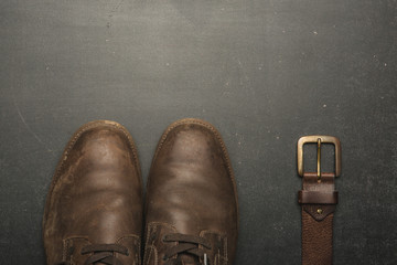 classic brown shoes and belt on wooden table. vintage picture