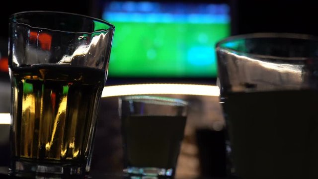 Blurred image of sport bar with TV and drinks in foreground