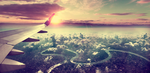 Fototapeta Concepto de viaje en avión .Volando sobre la ciudad hacia el destino. Paisaje al atardecer sobre las nubes. obraz