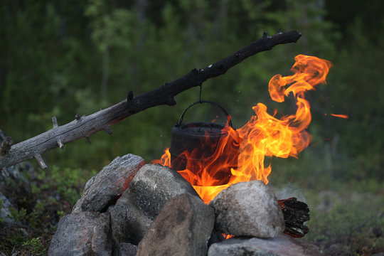 Wind and burning campfire with a kettle
