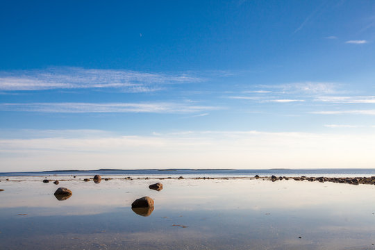 Stones and sky reflection in white sea low tide