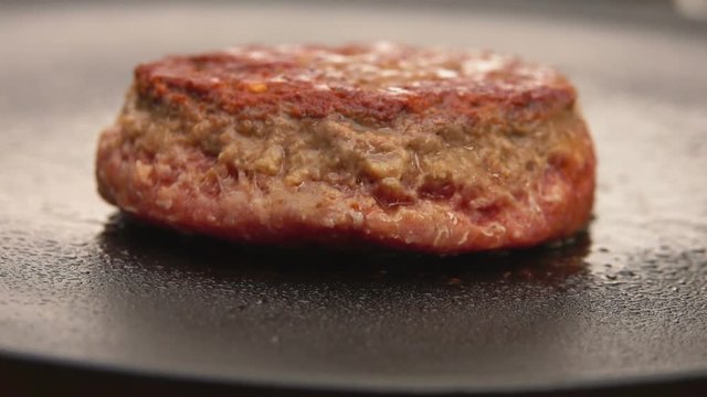 Burger flipped on the stone grill with kitchen spatula