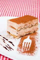 Delicious world famous Tiramisu cake on a white plate with decoration