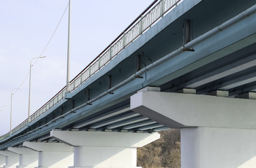 Piles under the bridge. Long concrete bridge across a wide river on a Sunny day