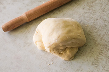 Dough for pizza and rolling-pin on wooden table
