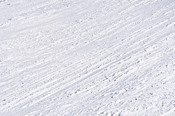Ski slope with traces of skis on a sunny day.
Background, texture.
