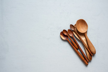 Wooden spoons of handmade different sizes close-up on a pile lie on a gray background.