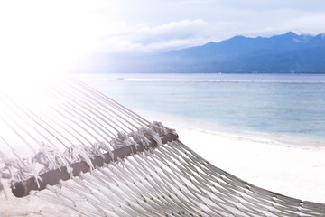 Hammock on sandy beach on background of azure Bali Sea. Coast of the Gili Trawangan island, Indonesia.
