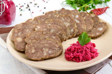 Home made dietary sausage from the liver on a white wooden table. Sausage cut into pieces on a plate with horseradish sauce.