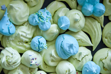 Fototapeta na wymiar tender color meringue dessert background. green and blue french candy. whipped egg white.
