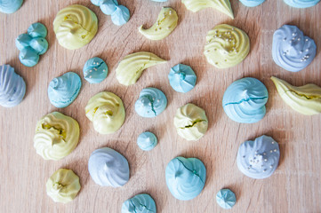 trendy french cookies flat lay. meringue top view background. sea shell dessert. green and blue color candy. whipped egg white sweets. marine mood with tasty meringues. silver luxury sprinkles pearl.