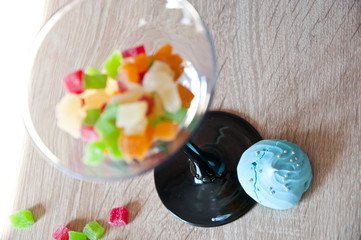 Close up of meringue and colorful candies in elegant glass.