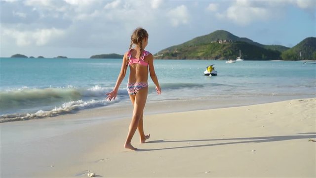 Adorable little girl have fun at tropical beach during vacation.